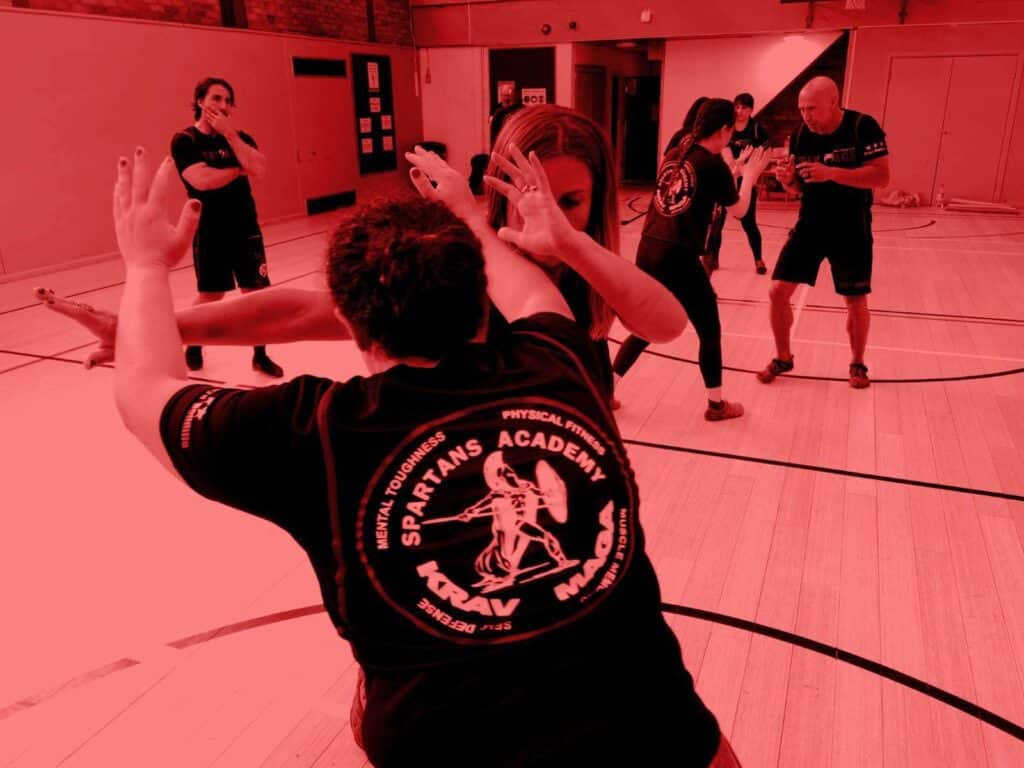 A group of people practicing self defence krav maga in a gym.