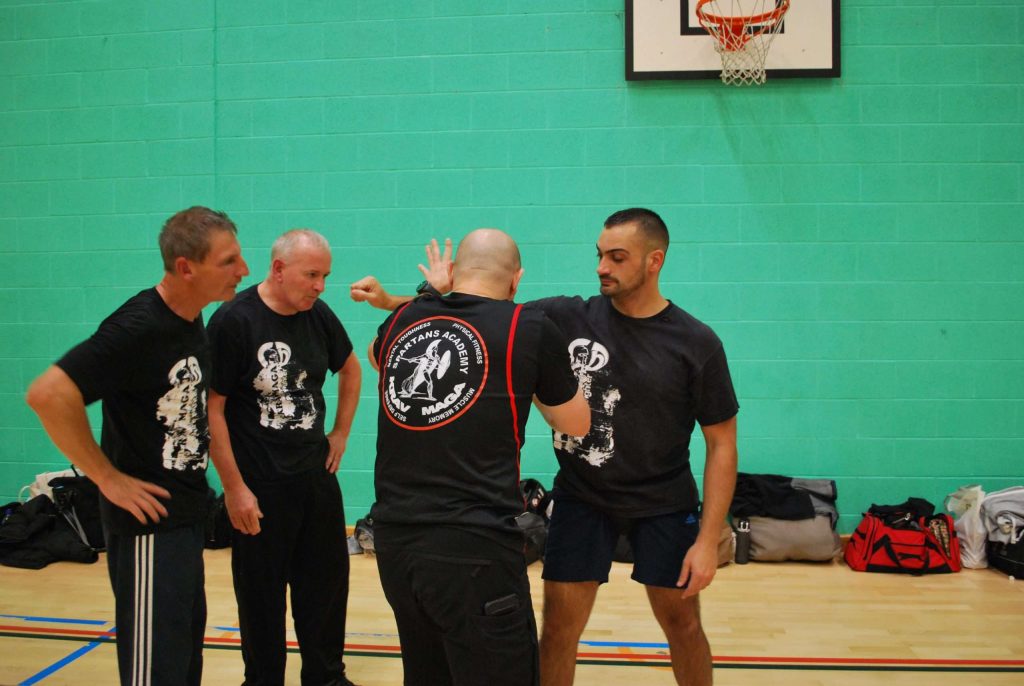 A group of men in black t - shirts standing in a gym.
