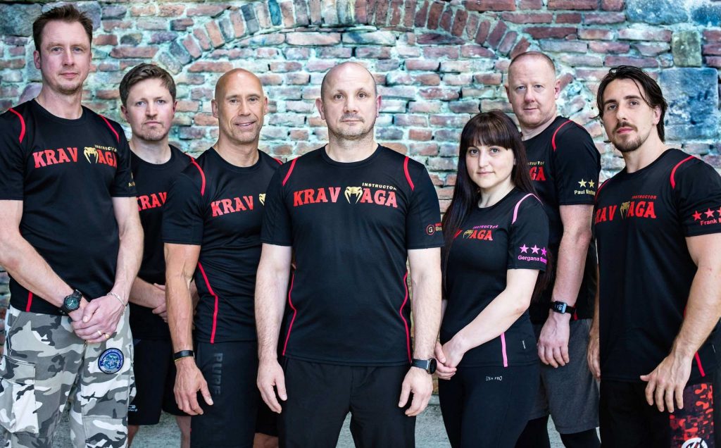 Our team of best krav maga trainers posing in front of a brick wall.